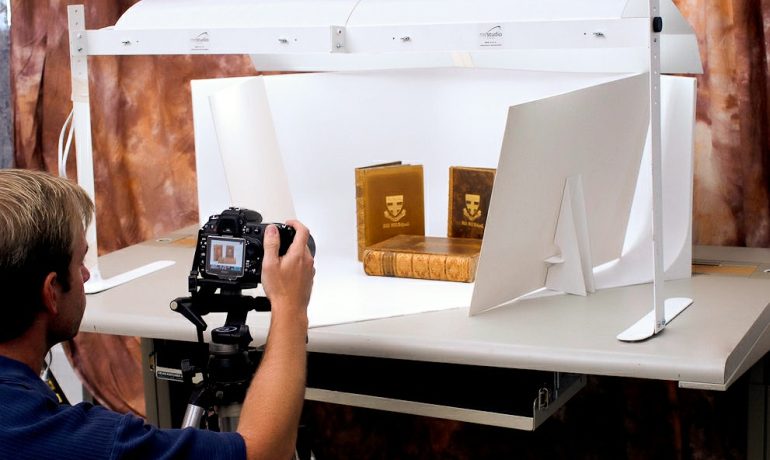 man taking picture of books in product photography lightbox