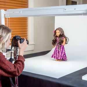 woman taking photo of doll in photo lightbox
